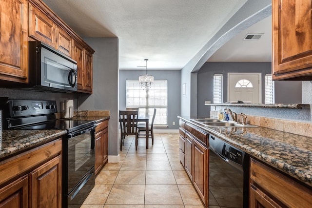 kitchen with sink, light tile patterned floors, dark stone countertops, a notable chandelier, and black appliances