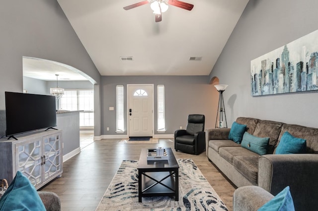 living room with hardwood / wood-style floors, ceiling fan with notable chandelier, and high vaulted ceiling