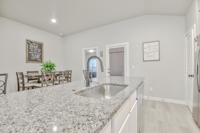 2927 Abbeville Ave, Wolfforth, TX 79382 - kitchen featuring a sink, light wood-type flooring, white cabinetry, light stone countertops, and baseboards