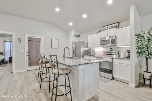 2927 Abbeville Ave, Wolfforth, TX 79382 - kitchen with appliances with stainless steel finishes, a sink, a breakfast bar, an island with sink, and white cabinetry