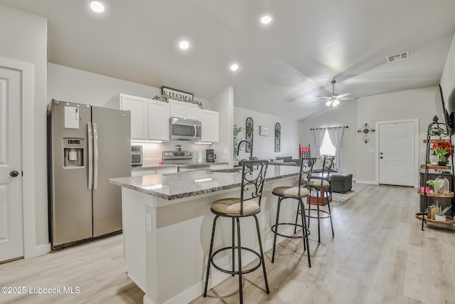 2927 Abbeville Ave, Wolfforth, TX 79382 - kitchen with appliances with stainless steel finishes, a sink, a breakfast bar area, lofted ceiling, and light wood finished floors