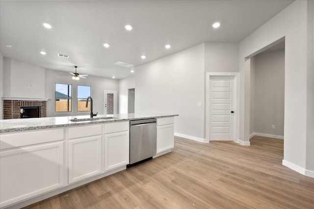 kitchen with white cabinetry, dishwasher, sink, light stone countertops, and light wood-type flooring