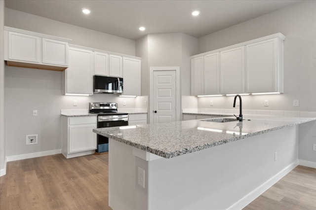 kitchen featuring appliances with stainless steel finishes, sink, white cabinets, light hardwood / wood-style floors, and kitchen peninsula