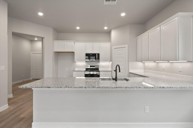 kitchen with sink, white cabinetry, appliances with stainless steel finishes, kitchen peninsula, and light stone countertops