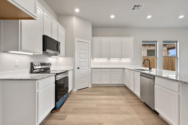 kitchen featuring appliances with stainless steel finishes, sink, white cabinets, light stone countertops, and light hardwood / wood-style flooring