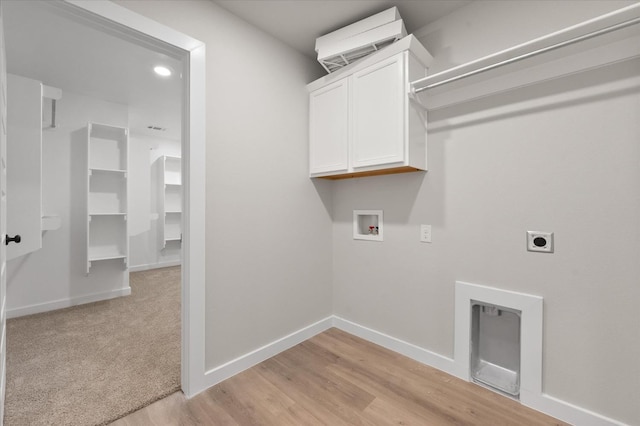 clothes washing area featuring a wall mounted air conditioner, cabinets, hookup for a washing machine, electric dryer hookup, and light wood-type flooring