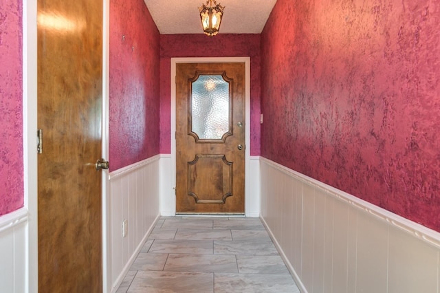 doorway to outside with a textured ceiling