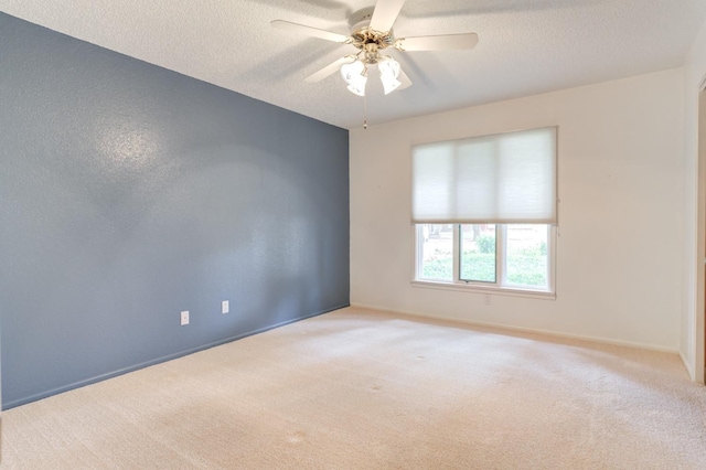 spare room featuring ceiling fan, light colored carpet, and a textured ceiling