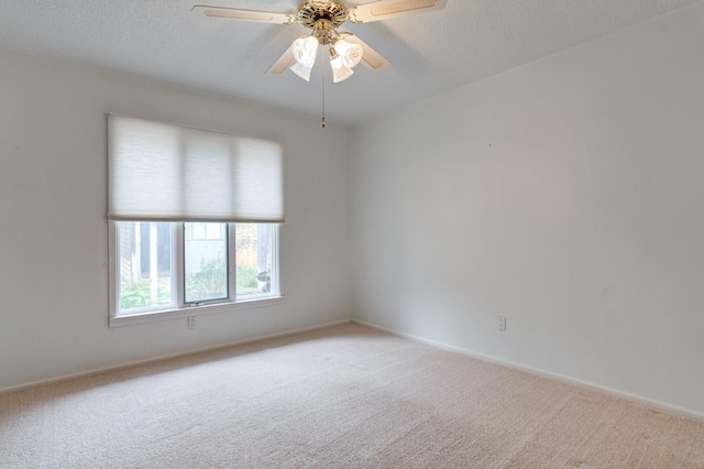 spare room with ceiling fan, light carpet, and a textured ceiling