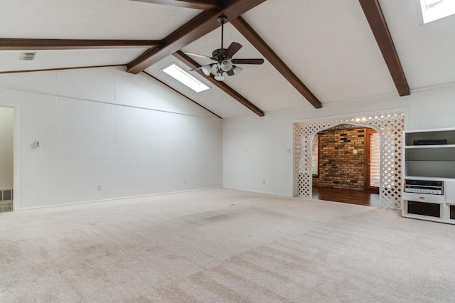 unfurnished living room with carpet flooring, vaulted ceiling with skylight, and ceiling fan