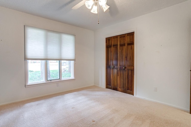 unfurnished room with ceiling fan, light carpet, and a textured ceiling