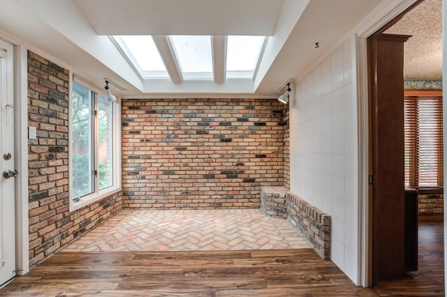 interior space featuring brick wall, dark wood-type flooring, and a skylight