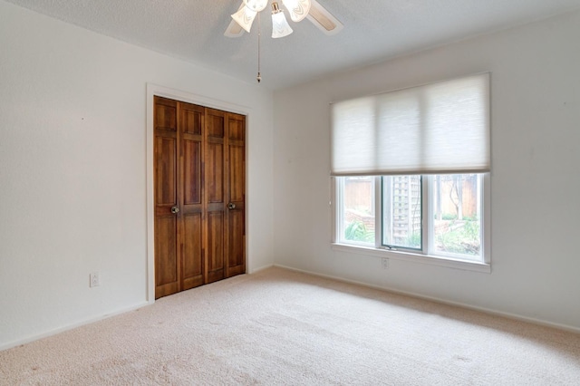 carpeted empty room featuring ceiling fan and a textured ceiling