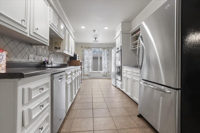 kitchen with tasteful backsplash, sink, white cabinets, light tile patterned floors, and stainless steel appliances