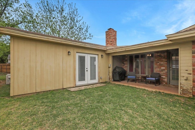 rear view of property with a lawn, a patio area, and french doors