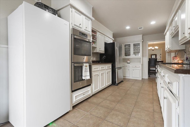 kitchen featuring stainless steel appliances, white cabinetry, sink, and an inviting chandelier