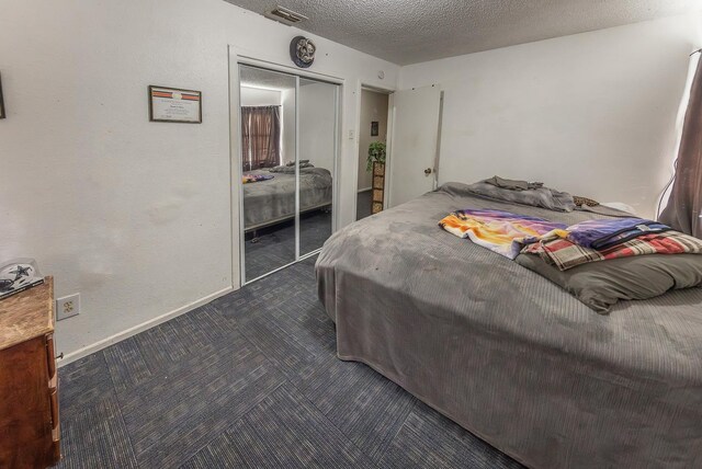 bedroom featuring dark colored carpet, a textured ceiling, and a closet