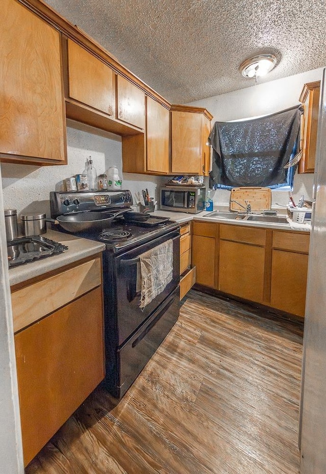 kitchen featuring hardwood / wood-style flooring, sink, a textured ceiling, and black / electric stove