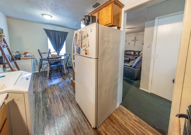 kitchen featuring dark hardwood / wood-style flooring, refrigerator, a textured ceiling, and washer / dryer