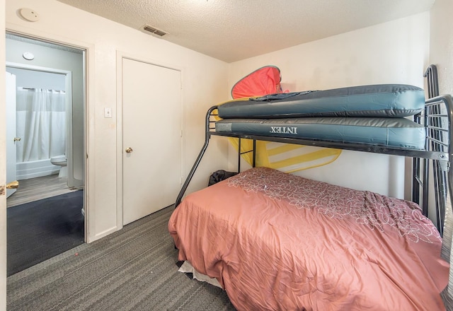 bedroom featuring a textured ceiling and dark colored carpet