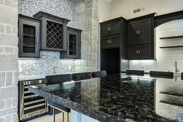 10704 Orlando Ave, Lubbock, TX 79423 - kitchen with glass insert cabinets, beverage cooler, decorative backsplash, and dark stone countertops