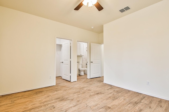 unfurnished bedroom with light hardwood / wood-style floors, a walk in closet, ceiling fan, and ensuite bath