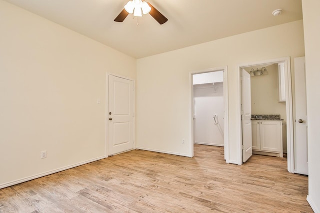 unfurnished bedroom featuring ceiling fan, a spacious closet, a closet, and light wood-type flooring