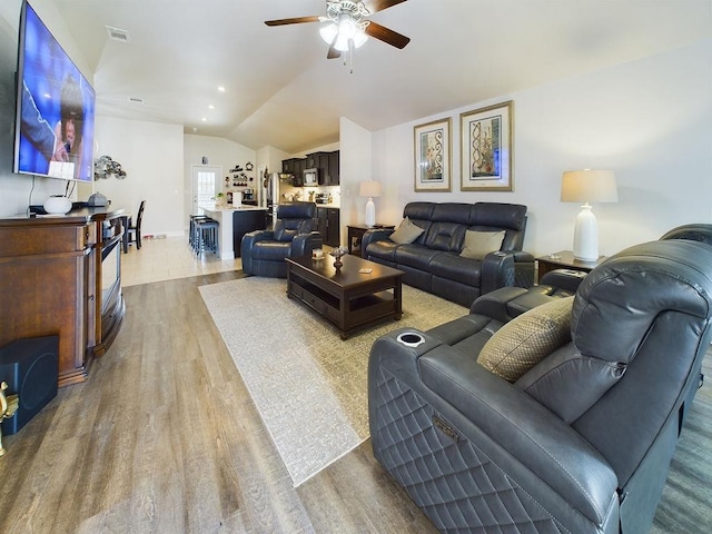 living room featuring lofted ceiling, ceiling fan, and light hardwood / wood-style flooring