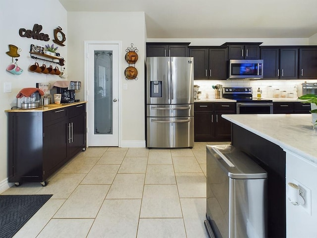 kitchen with light stone counters, light tile patterned floors, decorative backsplash, and stainless steel appliances