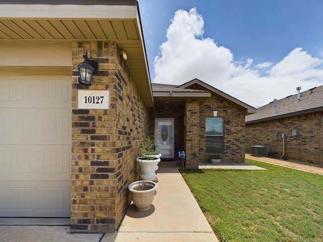 doorway to property featuring central AC, a yard, and a garage