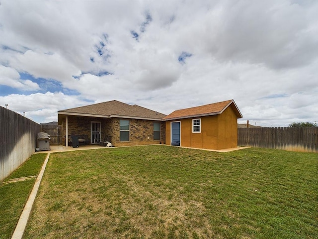 back of house featuring a yard, an outbuilding, and a patio