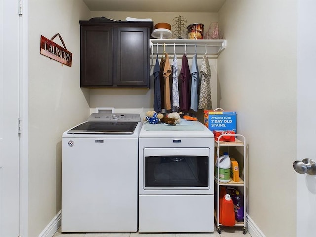 clothes washing area featuring washer and clothes dryer and cabinets