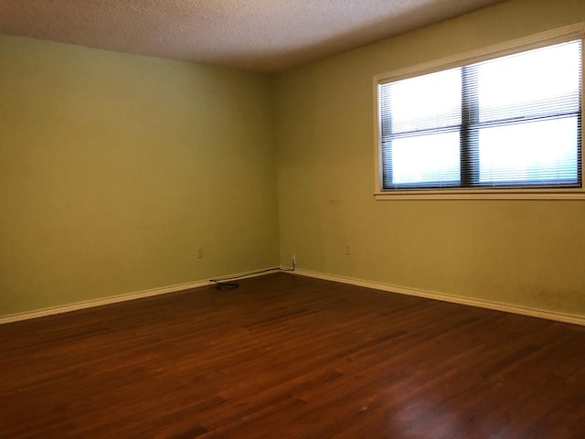 unfurnished room featuring dark hardwood / wood-style flooring and a textured ceiling