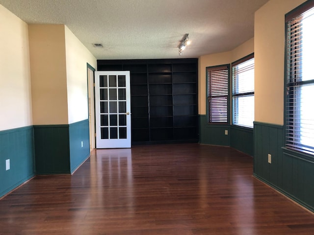 unfurnished room with dark hardwood / wood-style flooring and a textured ceiling