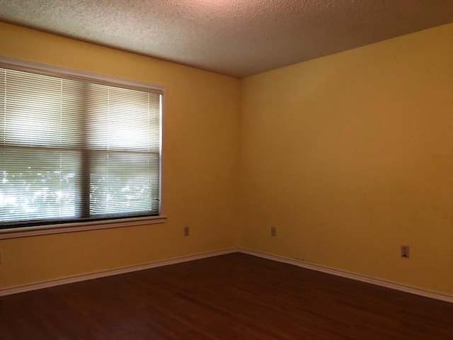 unfurnished room featuring dark wood-type flooring and a textured ceiling