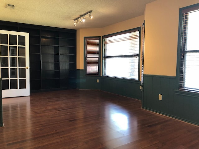 unfurnished room with dark hardwood / wood-style flooring, track lighting, built in features, and a textured ceiling