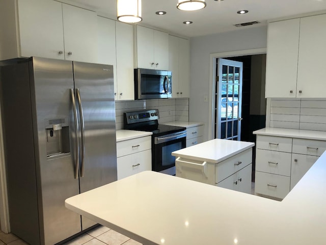 kitchen featuring light tile patterned floors, decorative backsplash, stainless steel appliances, and white cabinets