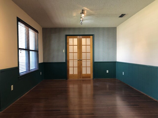 empty room featuring french doors, dark wood-type flooring, and a textured ceiling