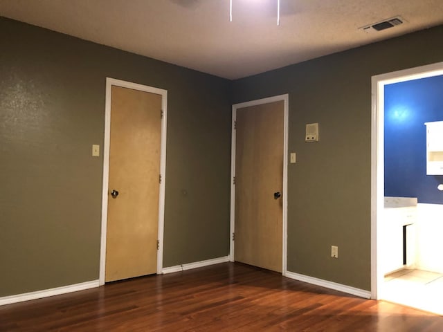 unfurnished bedroom with dark wood-type flooring and ensuite bath