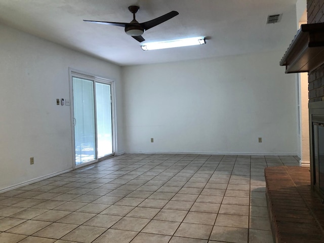 unfurnished living room with a brick fireplace, light tile patterned floors, and ceiling fan