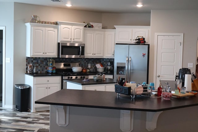 kitchen with appliances with stainless steel finishes, light hardwood / wood-style flooring, decorative backsplash, and white cabinets