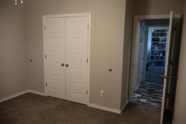 unfurnished bedroom featuring dark carpet and a closet