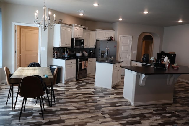 kitchen with white cabinetry, a center island, hanging light fixtures, appliances with stainless steel finishes, and a kitchen breakfast bar