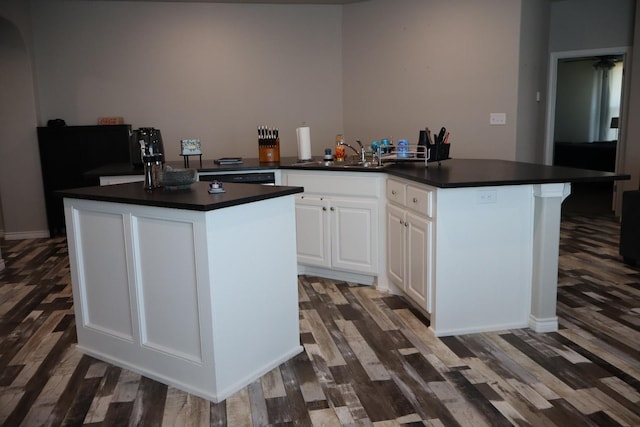 kitchen with white cabinetry, a kitchen island, sink, and dark wood-type flooring