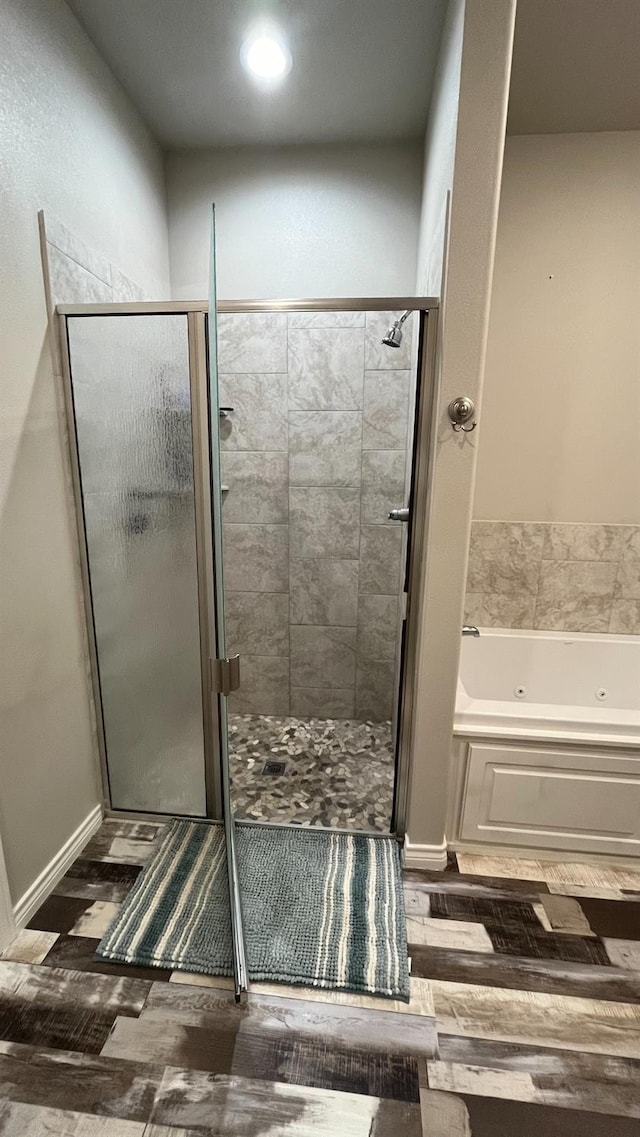 bathroom with independent shower and bath and hardwood / wood-style floors