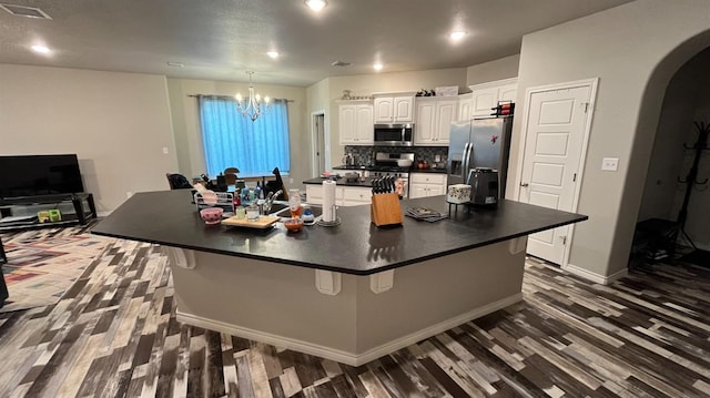 kitchen with a large island with sink, a kitchen breakfast bar, white cabinets, and appliances with stainless steel finishes