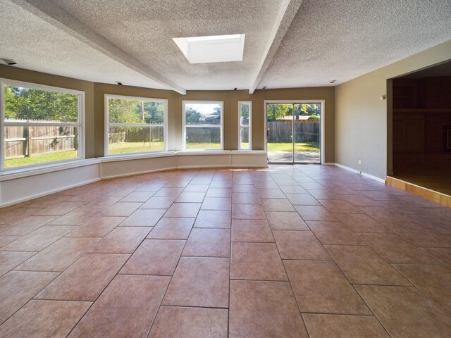 unfurnished room featuring light tile patterned floors, a skylight, and a textured ceiling