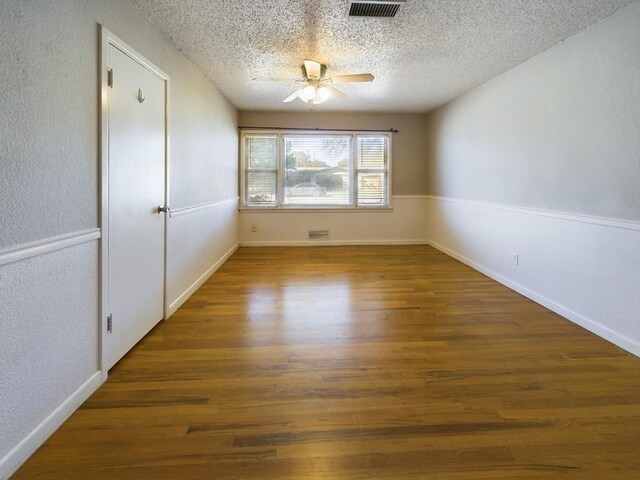 empty room featuring a textured ceiling, dark wood-type flooring, and ceiling fan