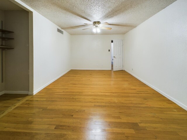 empty room with hardwood / wood-style flooring, a textured ceiling, and ceiling fan