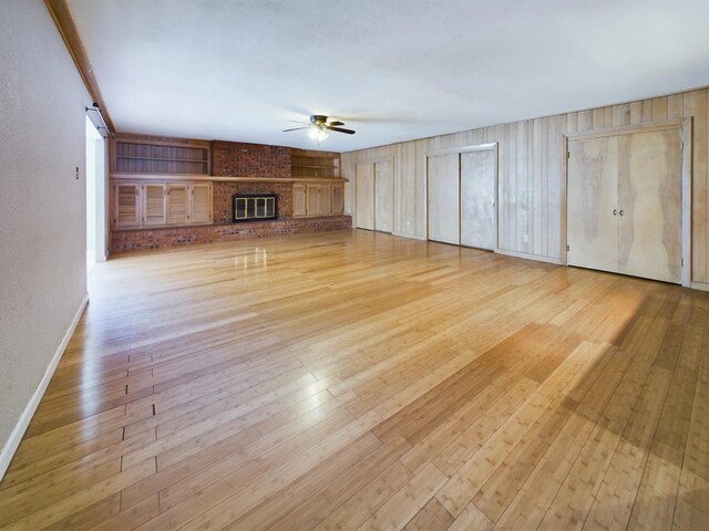 unfurnished living room with ceiling fan, light hardwood / wood-style floors, and a brick fireplace